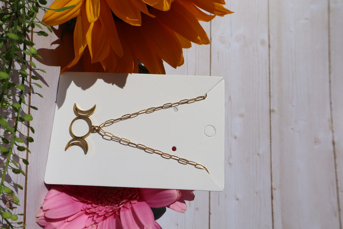 Gold-filled triple moon pendant necklace displayed on jewelry card with flowers